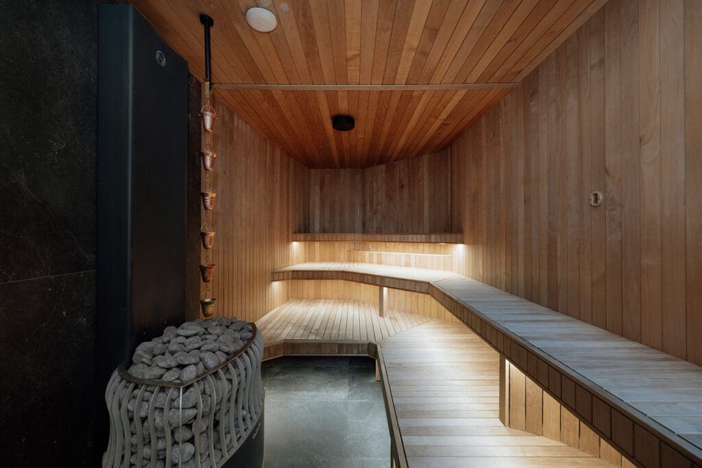 Wooden sauna interior with benches and a sauna stove.